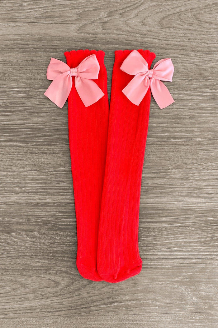 Red & Pink Bow Socks - Default Title - Knee-high red ribbed socks with large pink bows at the top on a wooden floor background.