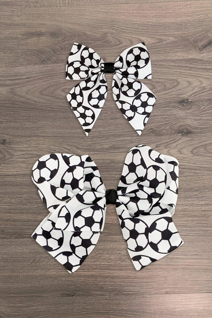 Soccer Bows - Small - Two black and white soccer ball print hair bows, one small and one large, on wood surface.