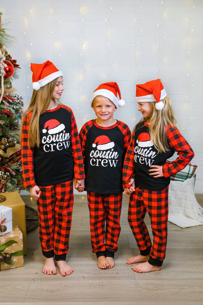 "Cousin Crew" Buffalo Plaid Pajamas - 3XS-6-12 Months - Kids wearing red and black buffalo plaid pajamas with black tops reading "cousin crew" and Santa hats.